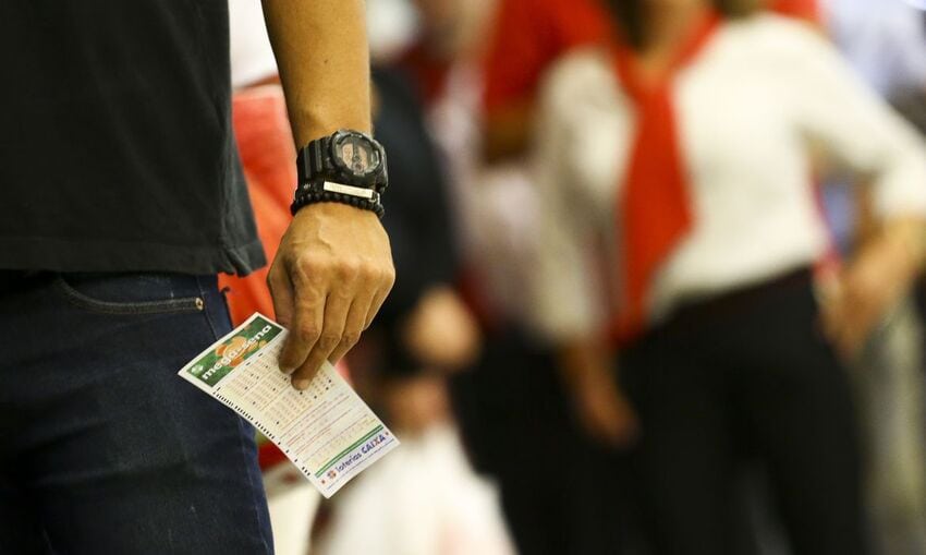 Apostador com bilhete da Mega- Sena na mão