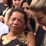 Muito emocionada, mãe é amparada durante enterro da filha.