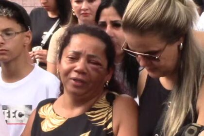 Muito emocionada, mãe é amparada durante enterro da filha.